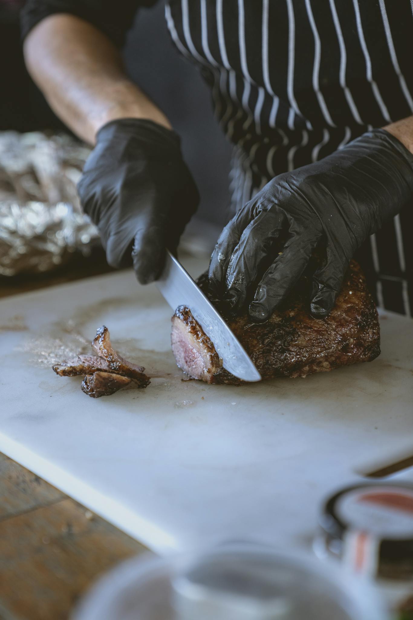 A chef expertly slices grilled steak on a cutting board, showcasing culinary skills.